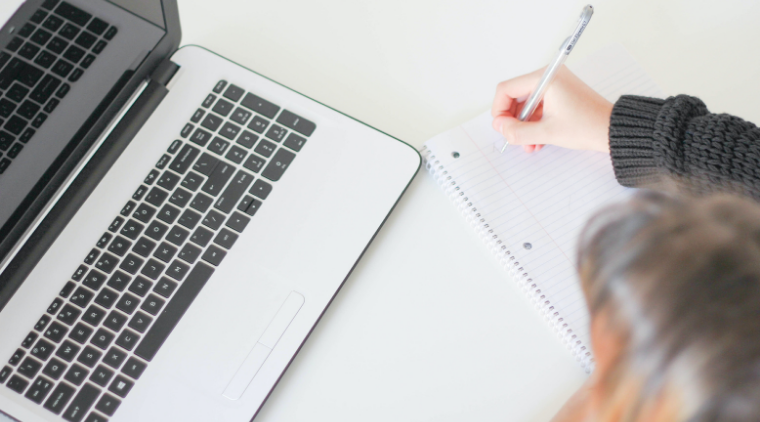 Person studying with laptop and notebook.