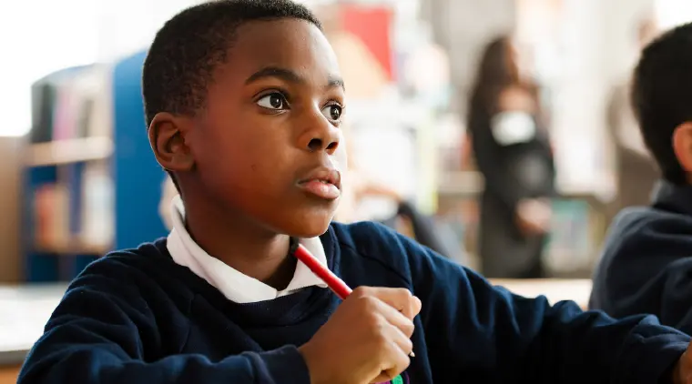 Boy in school uniform looking thoughtfully to the side.