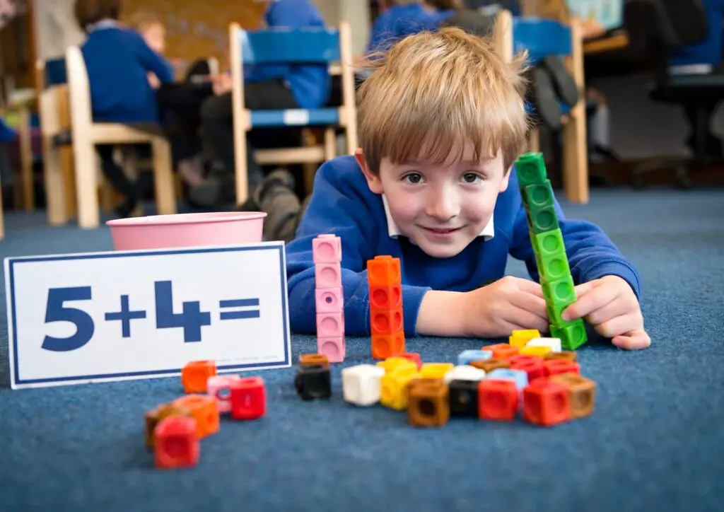 Primary school student learning addition with colorful blocks.