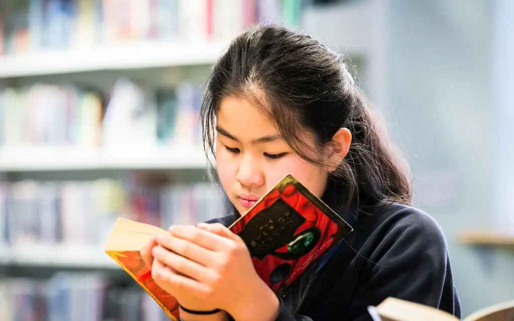 Student reading a book in a library.