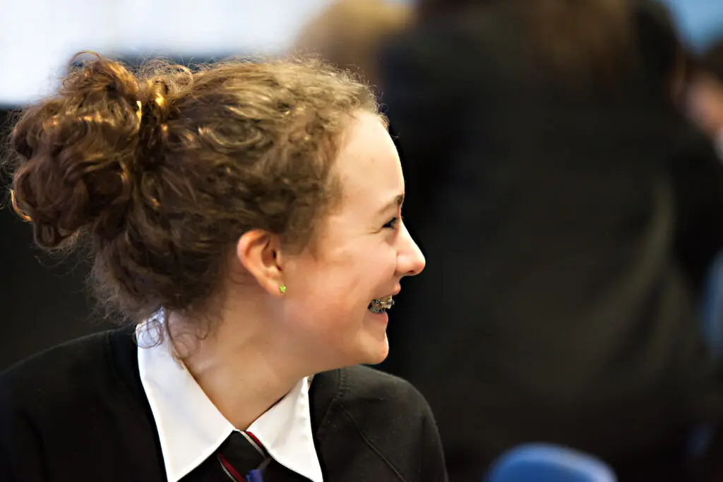 Smiling girl in school uniform looking right.