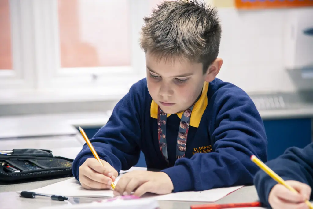 Young schoolboy in uniform concentrating on his work at a desk.