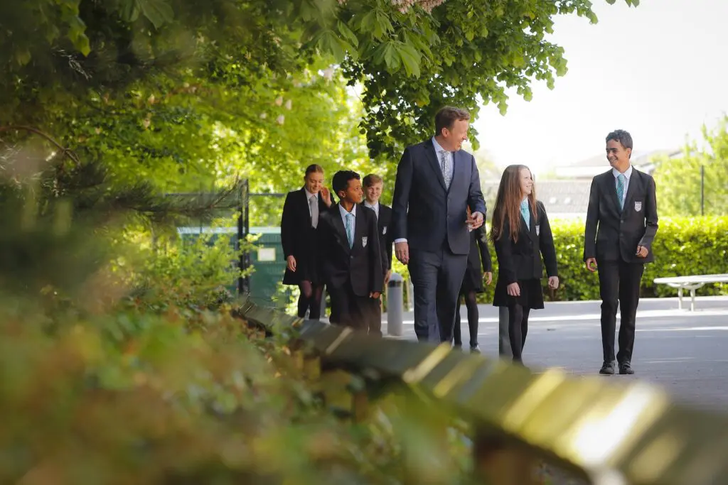 Kieran Scanlon walking with students in school uniforms on a school campus with greenery.