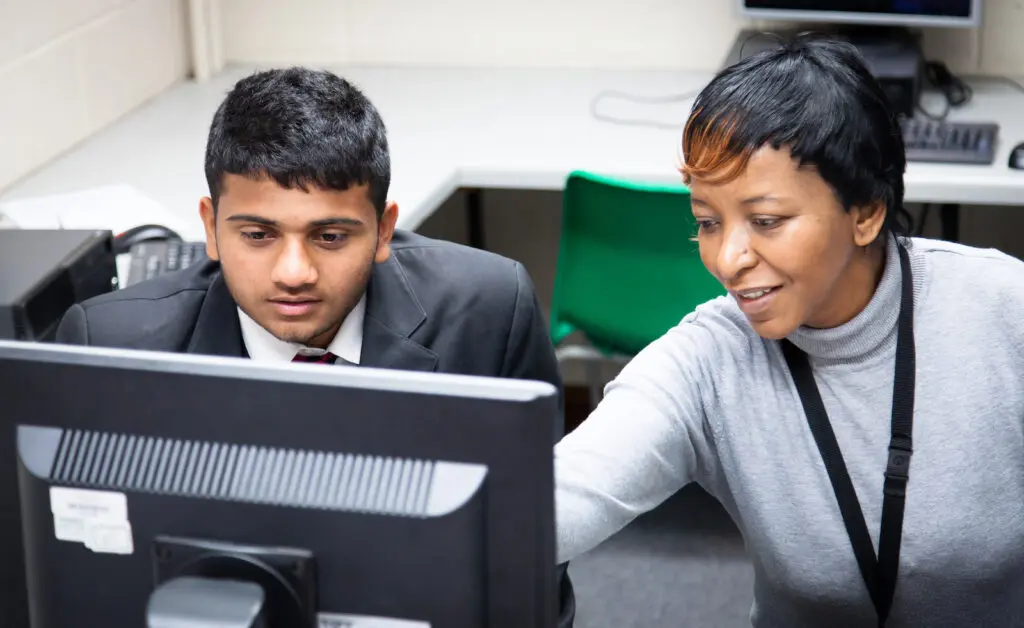Student and teacher work together looking at a computer screen.