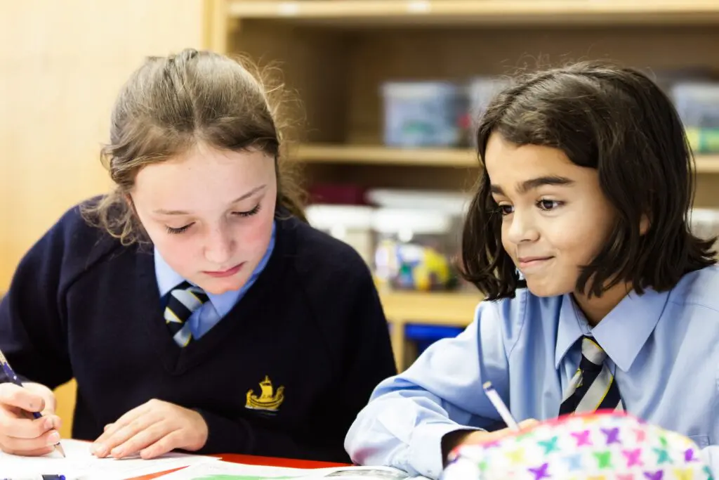 Two schoolgirls in uniform working at their desks.