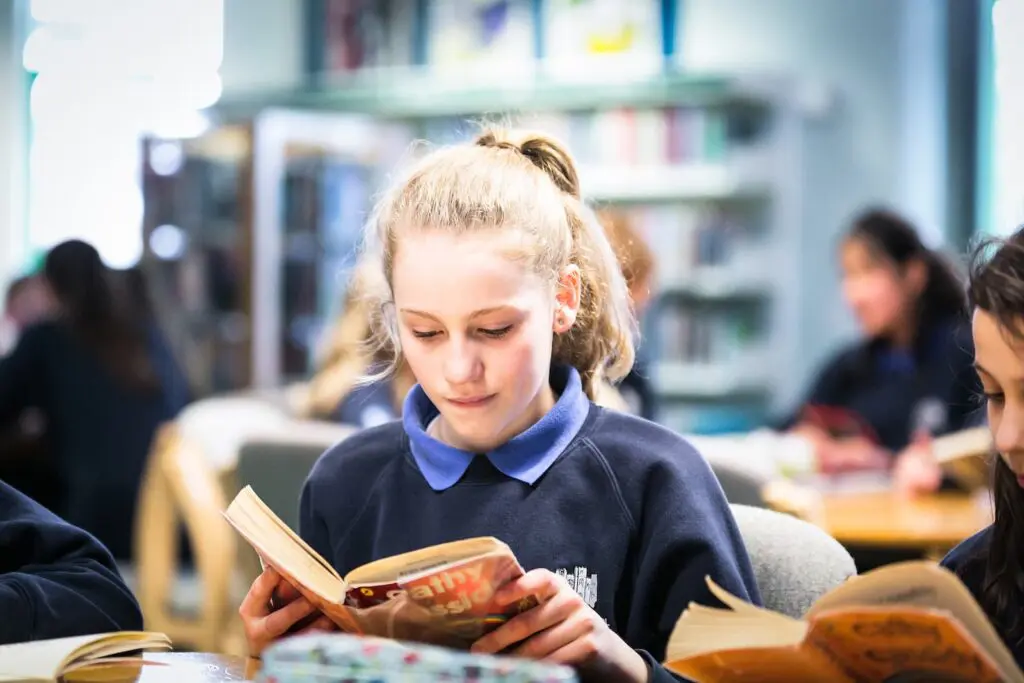 Schoolgirl reading a book in the library.