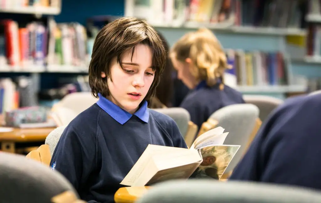 Student reading a book in a library.