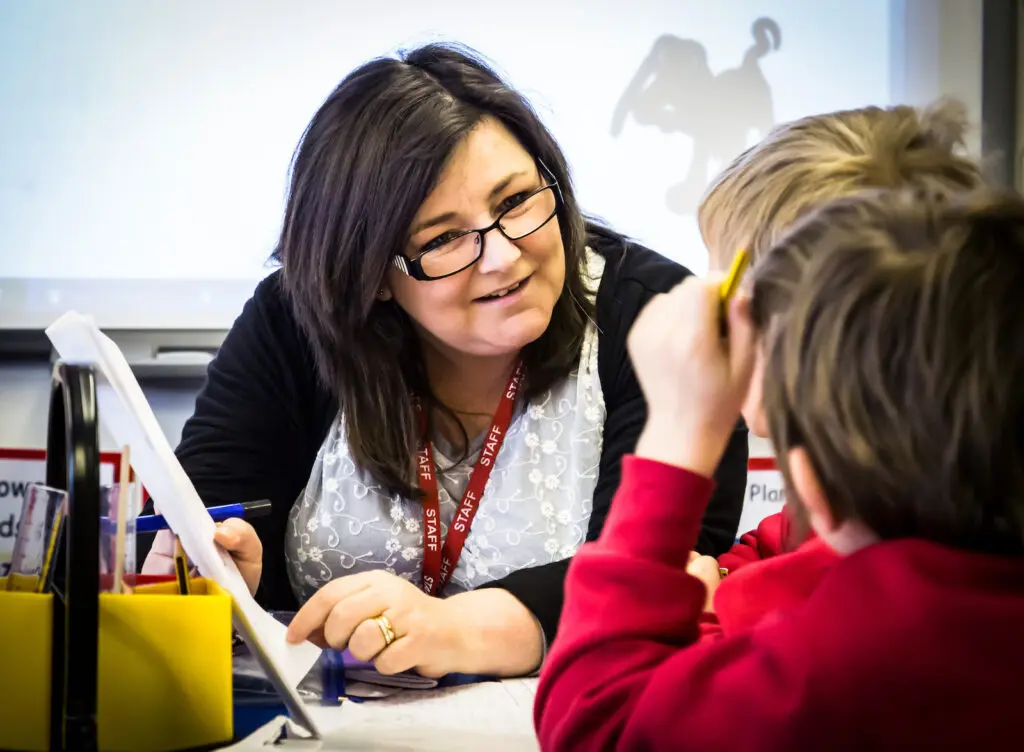 Teacher working with students in a classroom setting.