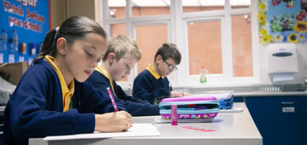 Primary school students working at their desks in a classroom.