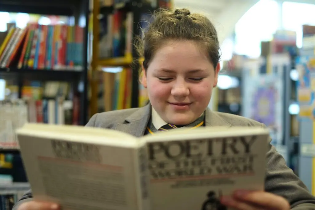 Student in school uniform reading in a library.