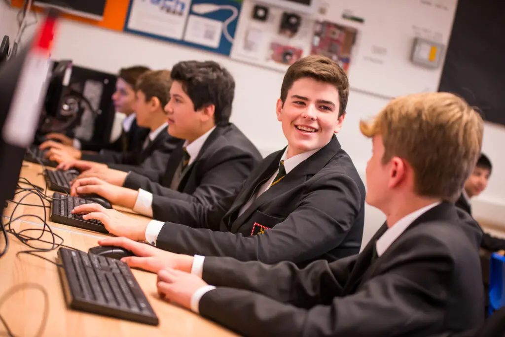 Students in school uniforms working on computers in a classroom.