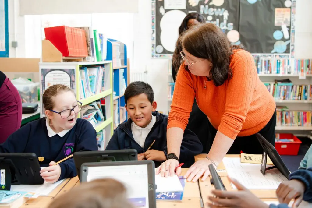Teacher helping students who are using tablets