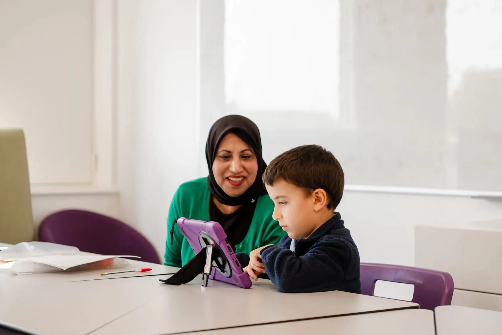 Teacher helping student who is using a tablet